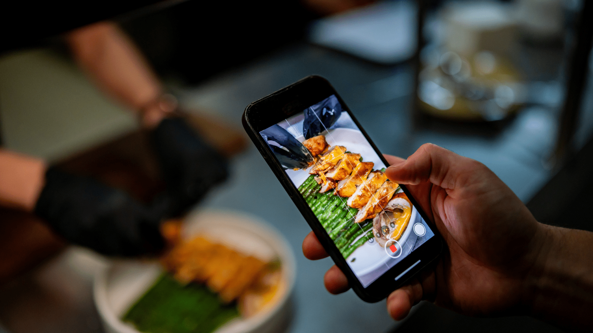 Person recording a restaurant dish on a smartphone to create video content for marketing