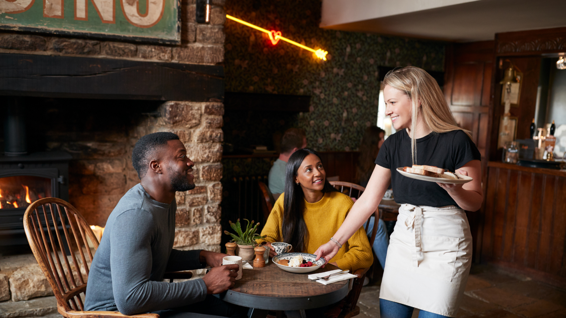 Restaurant server smiling and interacting with guests while serving food at their table
